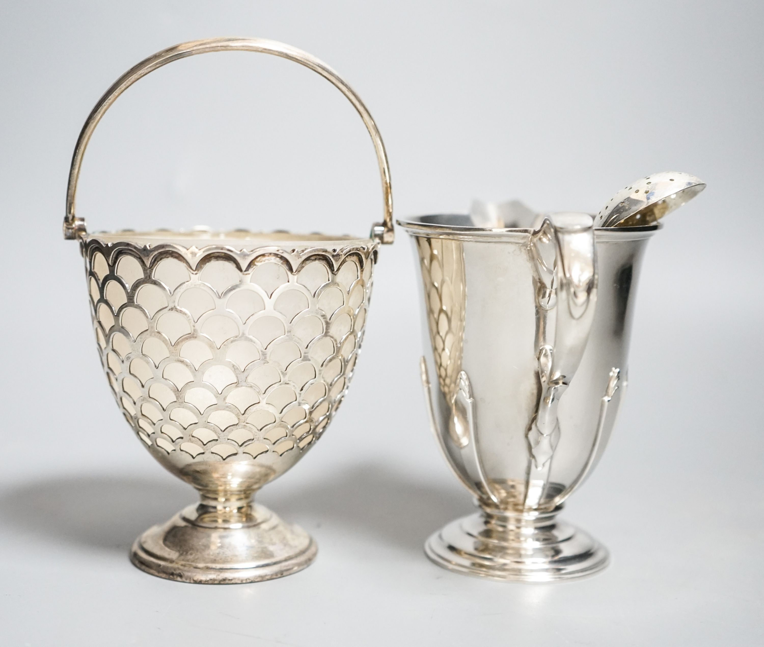 A modern silver sugar basket and sifter spoons, with glass liner by Mappin & Webb, 9.8cm and an earlier silver cream jug by William Comyns & Sons Ltd.